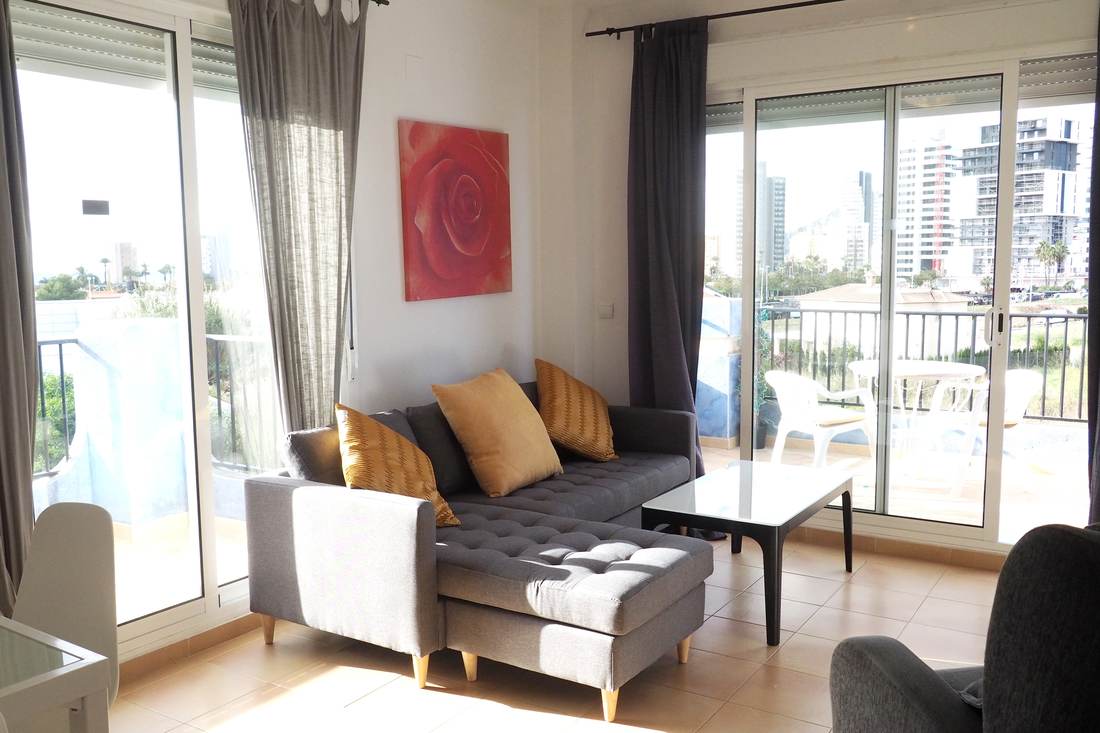Salón con el sofá gris, la butaca y la puerta corredera a la terraza