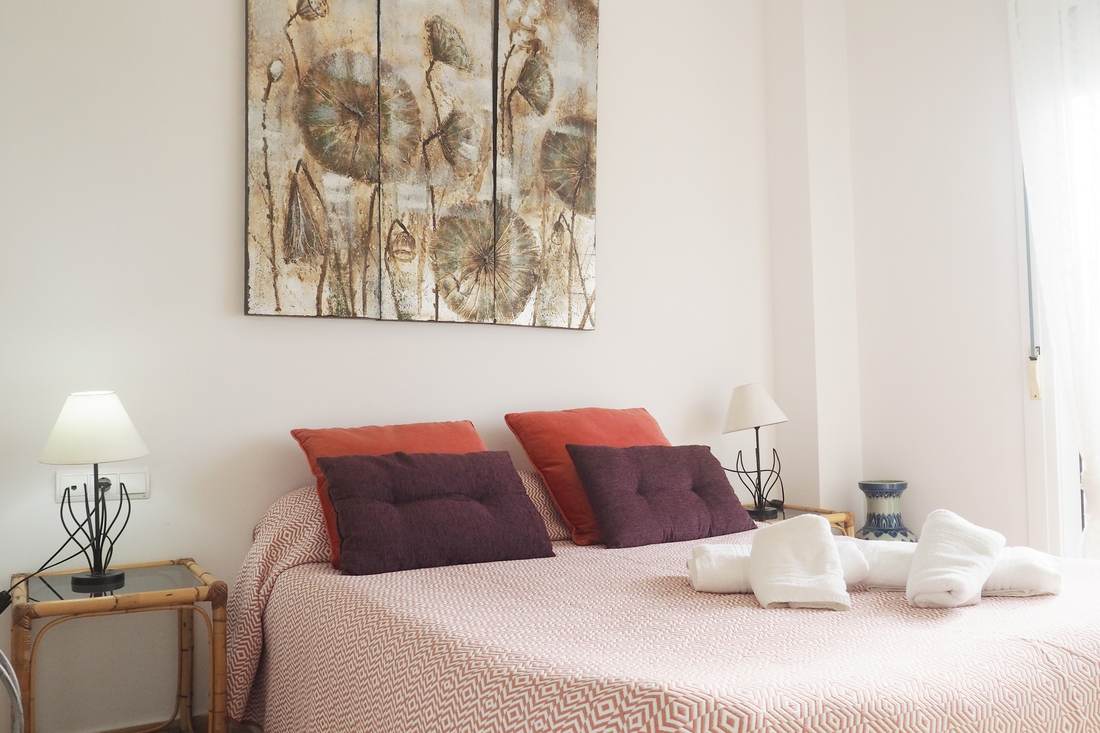 Dormitorio doble con cojines rojos y las mesillas a los lados