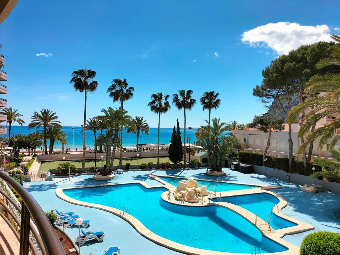 La piscina de la urbanización y el mar vistos desde la terraza del apartamento