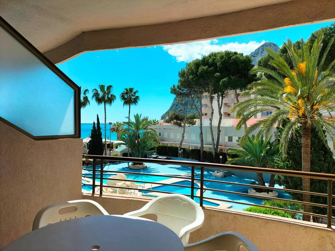 Terraza del apartamento con mesa y sillas, asomada a la piscina