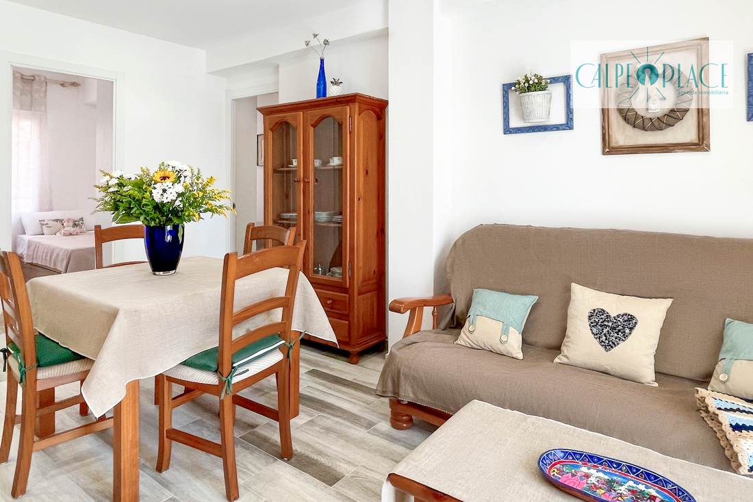 El salón con el sofá y la mesa de comedor al fondo