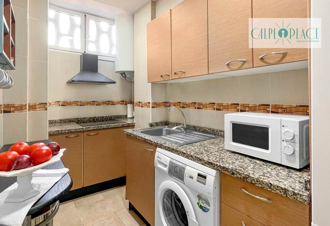 Cocina con encimera de granito, microondas y lavadora