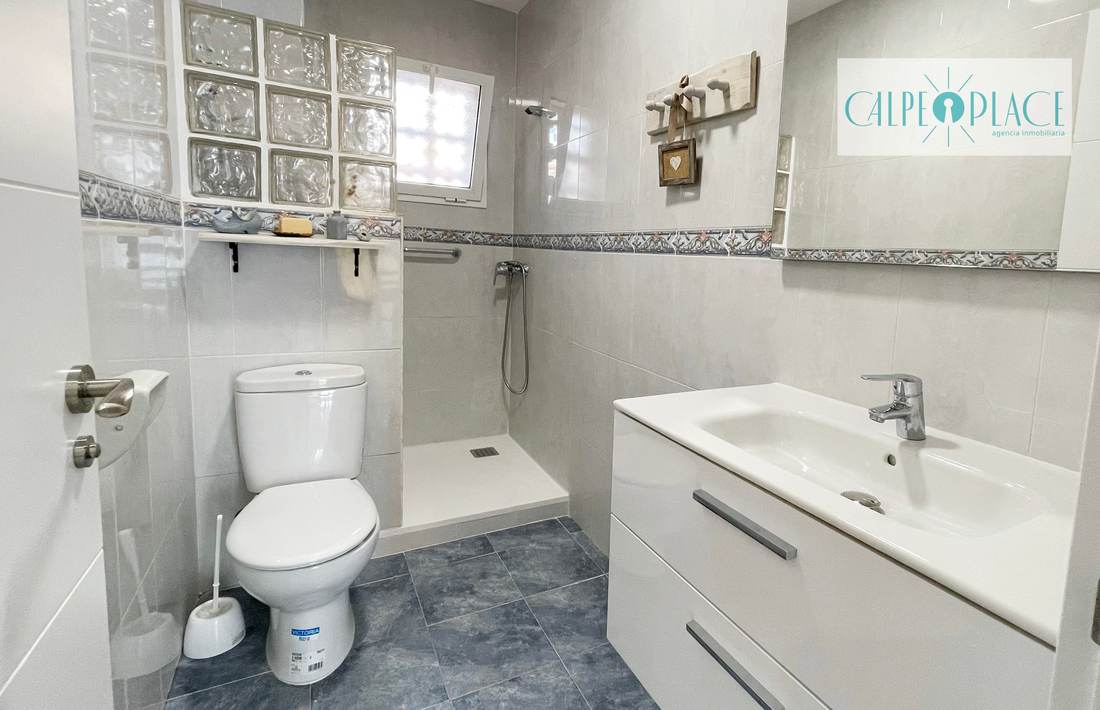 Baño con ducha, mampara y mueble de lavabo blanco
