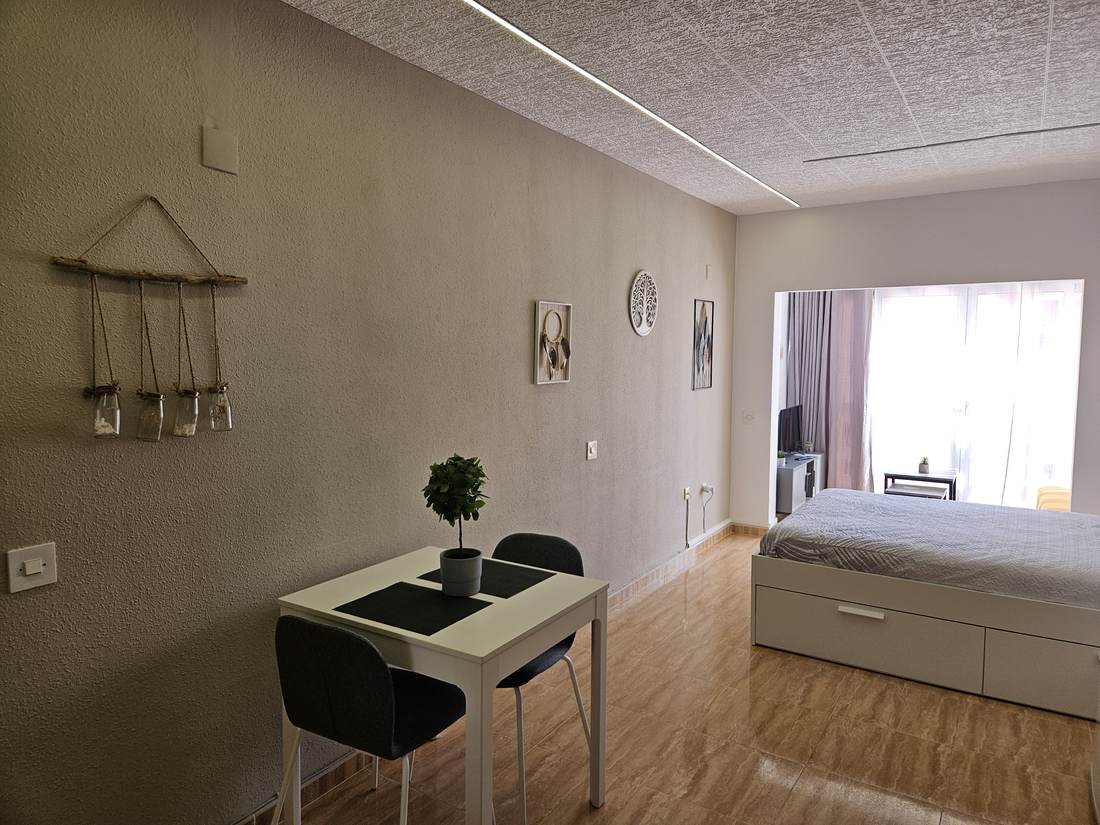 La mesa de comedor con la cama al fondo