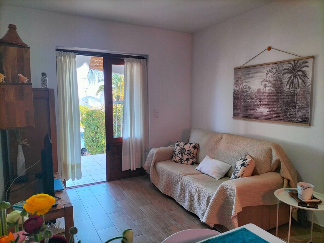 Salón con sofá y la puerta abierta a la terraza
