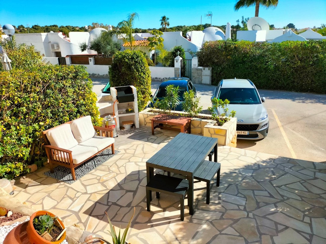 Terraza delantera con sofá de exterior, mesa y barbacoa