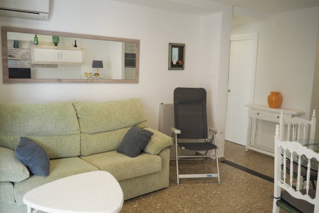Salón con sofá, butaca y el espejo largo sobre la pared