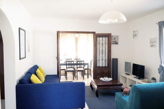 Salón-comedor de Casa Clara con los sofás azules y la mesa de comedor al fondo