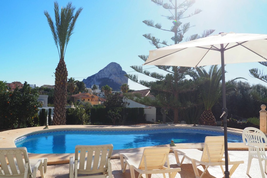 Zona de tumbonas y sombrilla junto a la piscina, con el Peñón detrás