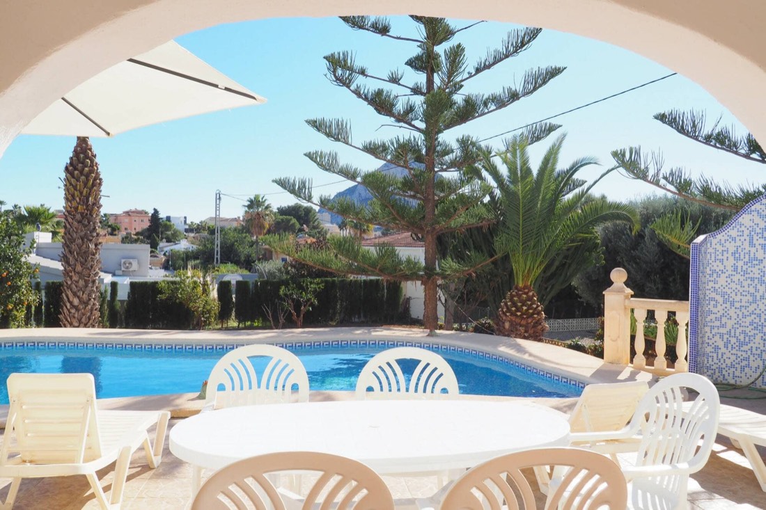 Mesa y sillas de verano bajo el arco del porche, junto a la piscina