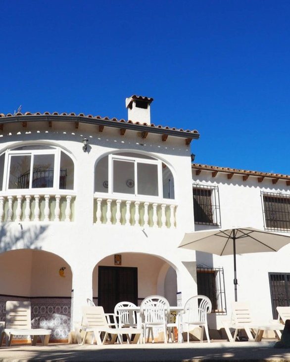 Fachada de Casa Margarita con el mirador acristalado, la sombrilla y las sillas de la terraza
