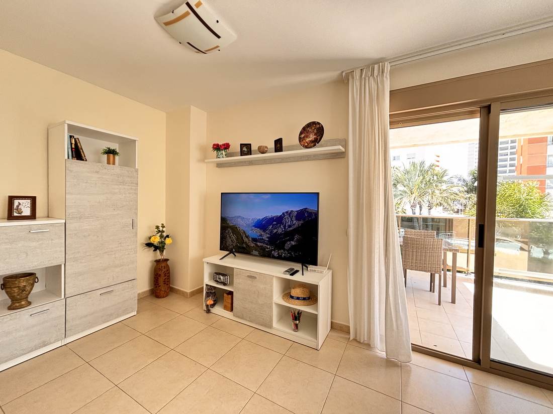 Salón con sofá, televisión y salida a la terraza