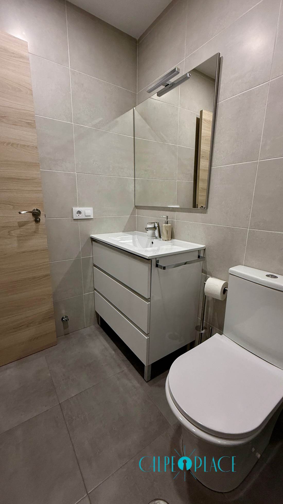 Baño reformado con mueble de lavabo y espejo