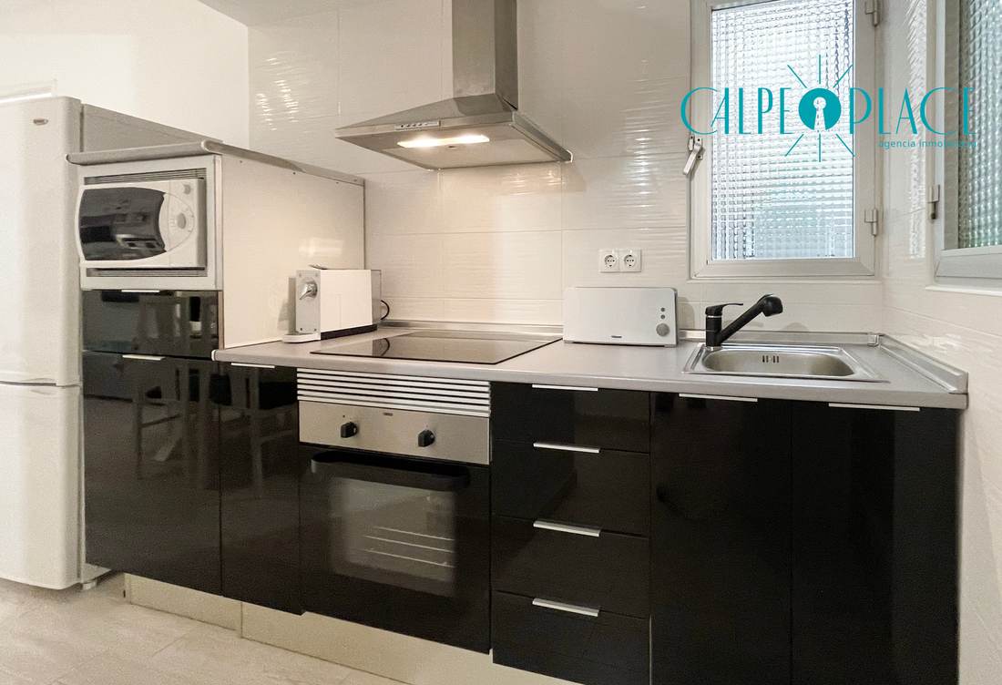 Cocina negra con microondas, vitrocerámica y fregadero