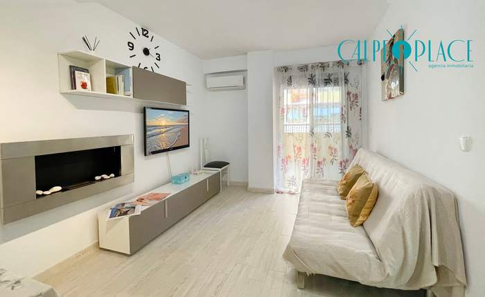 Salón de Jardín con el sofá blanco y el mueble bajo de televisión