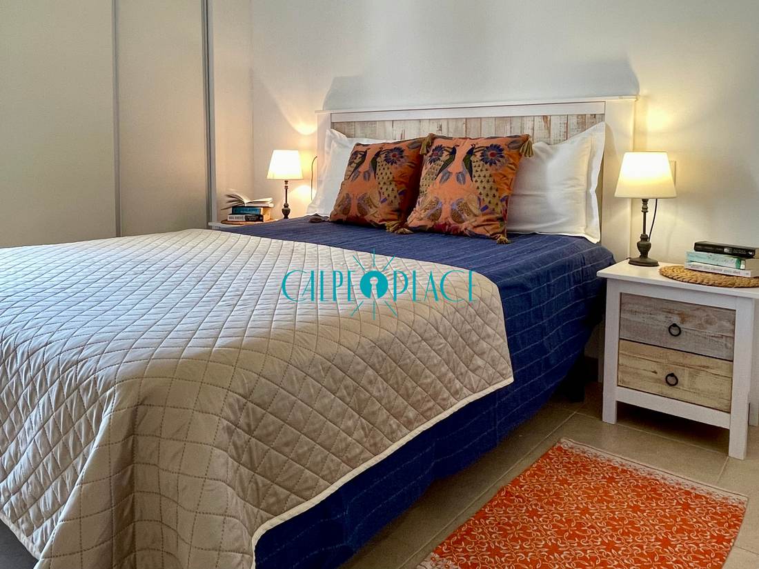 Dormitorio doble con colcha azul y una mesilla a cada lado