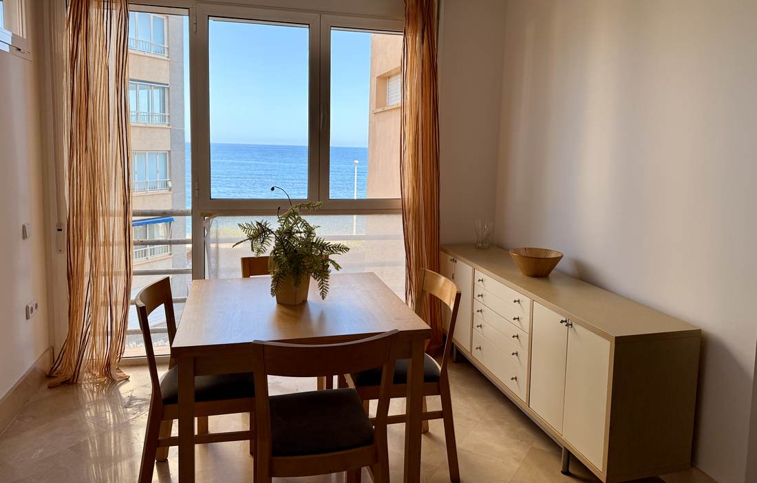 Rincón de comedor junto a la galería, con el mar al otro lado del cristal