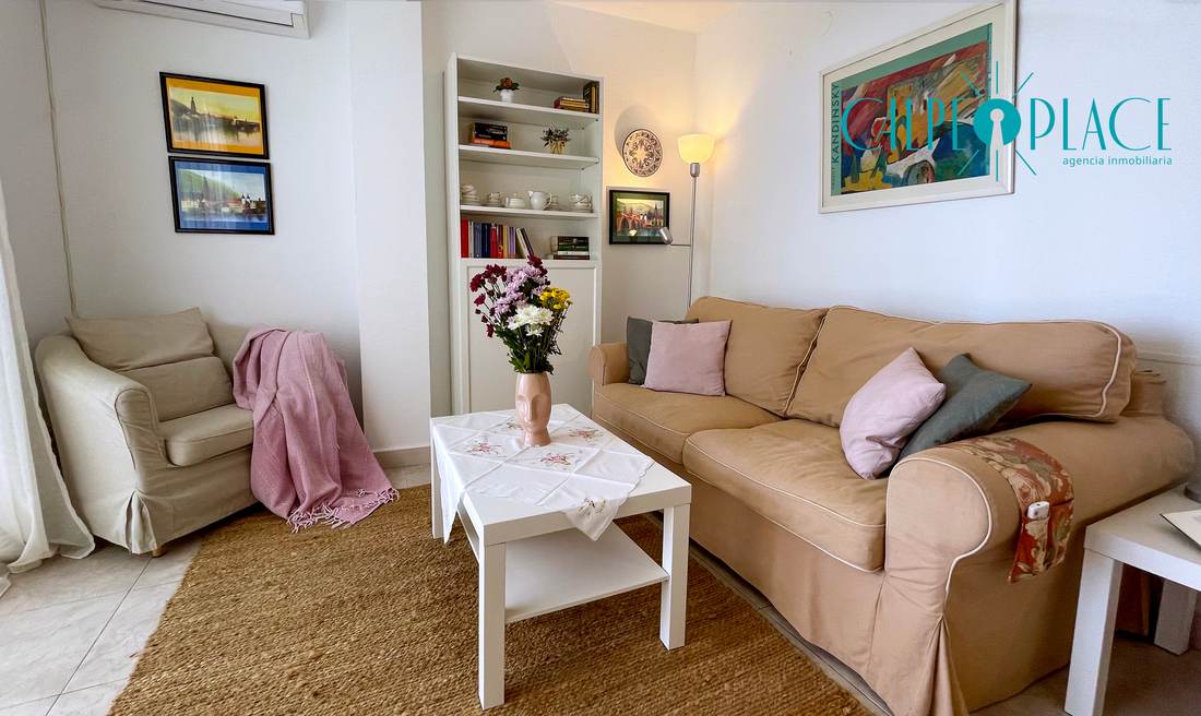 Salón con sofá beige, butaca y estanterías de obra
