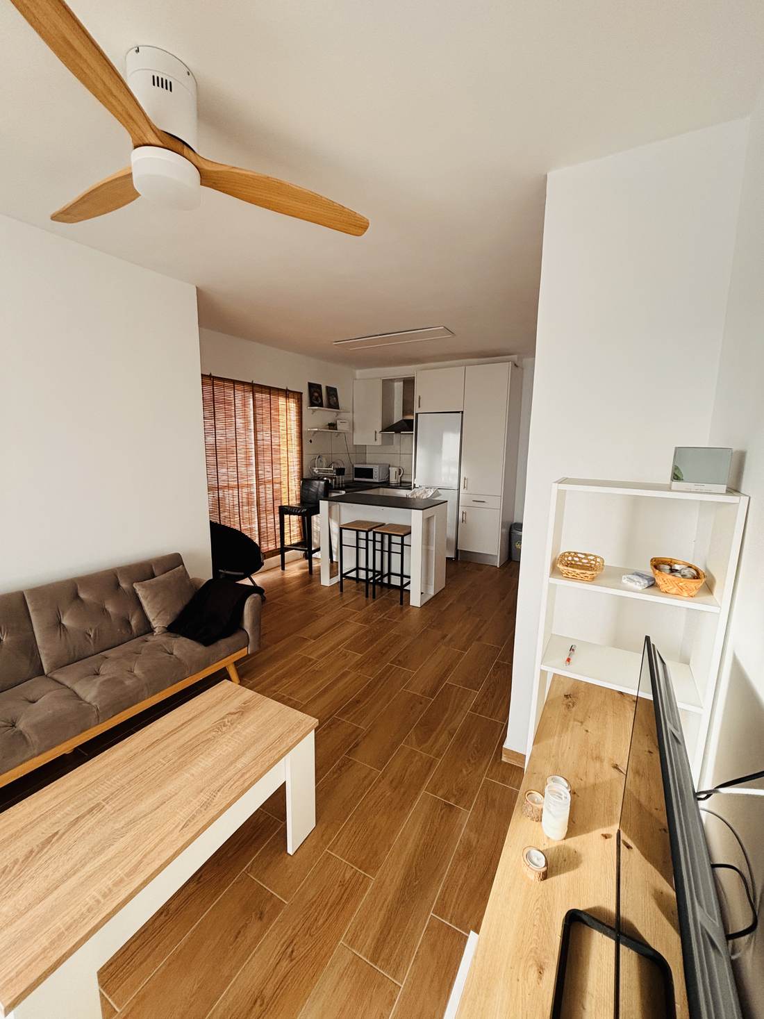 Salón de Porto Bello con sofá de piel y la cocina abierta al fondo