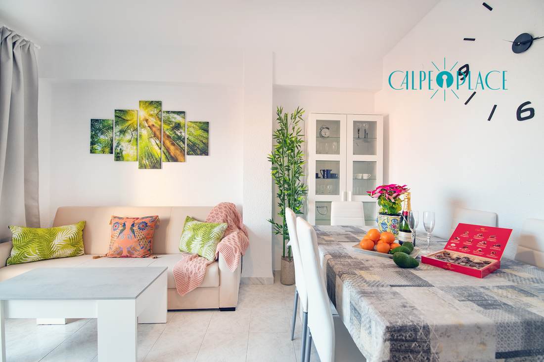 Salón de Tucán con el sofá blanco, la mesa de comedor y la puerta a la terraza