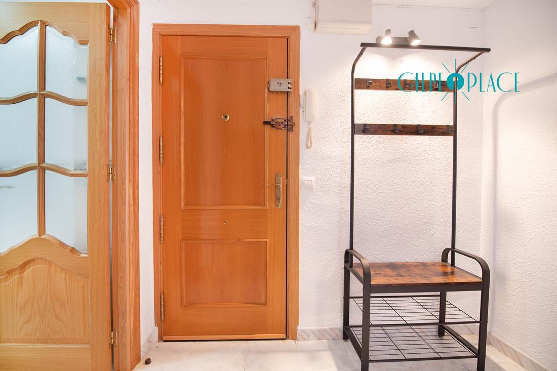 La entrada, con la puerta de madera y el perchero