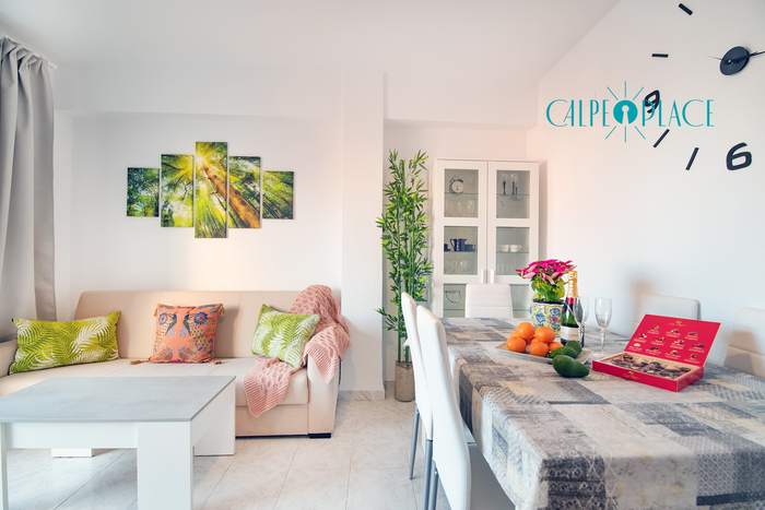 Salón de Tucán con el sofá blanco, la mesa de comedor y la puerta a la terraza