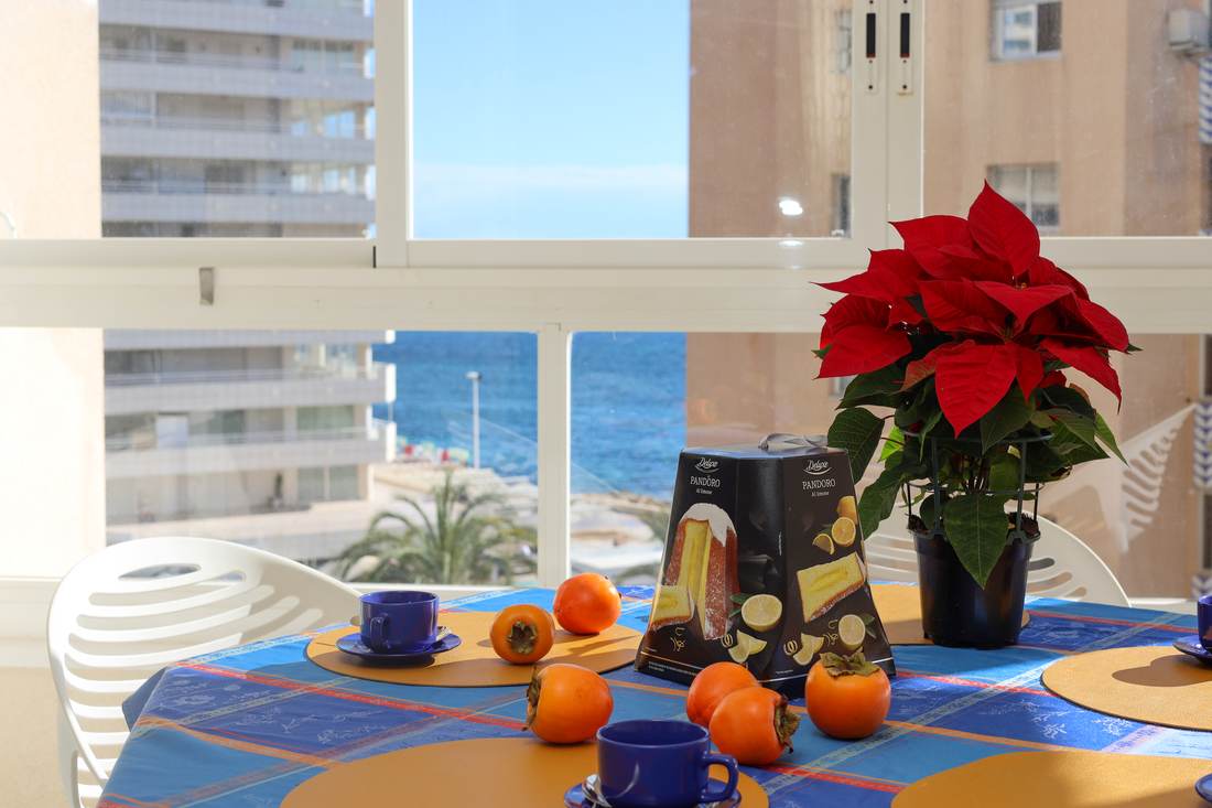 Mesa de comedor junto al ventanal, con el mar al fondo