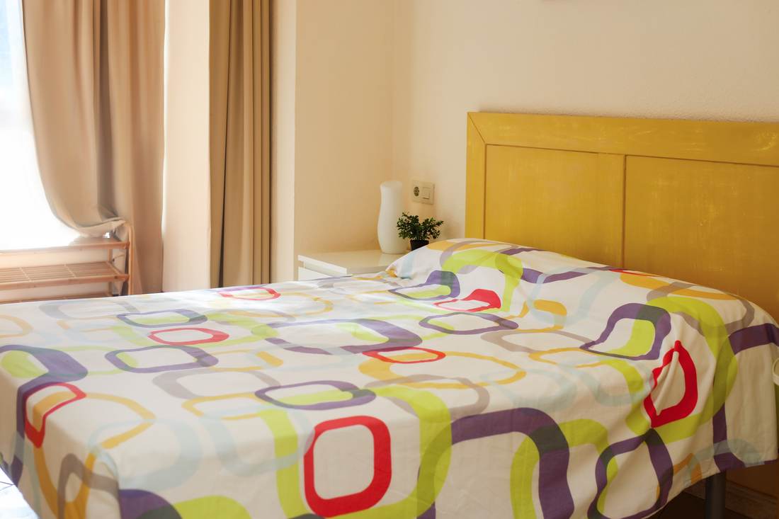 Dormitorio con colcha de colores y cabecero amarillo