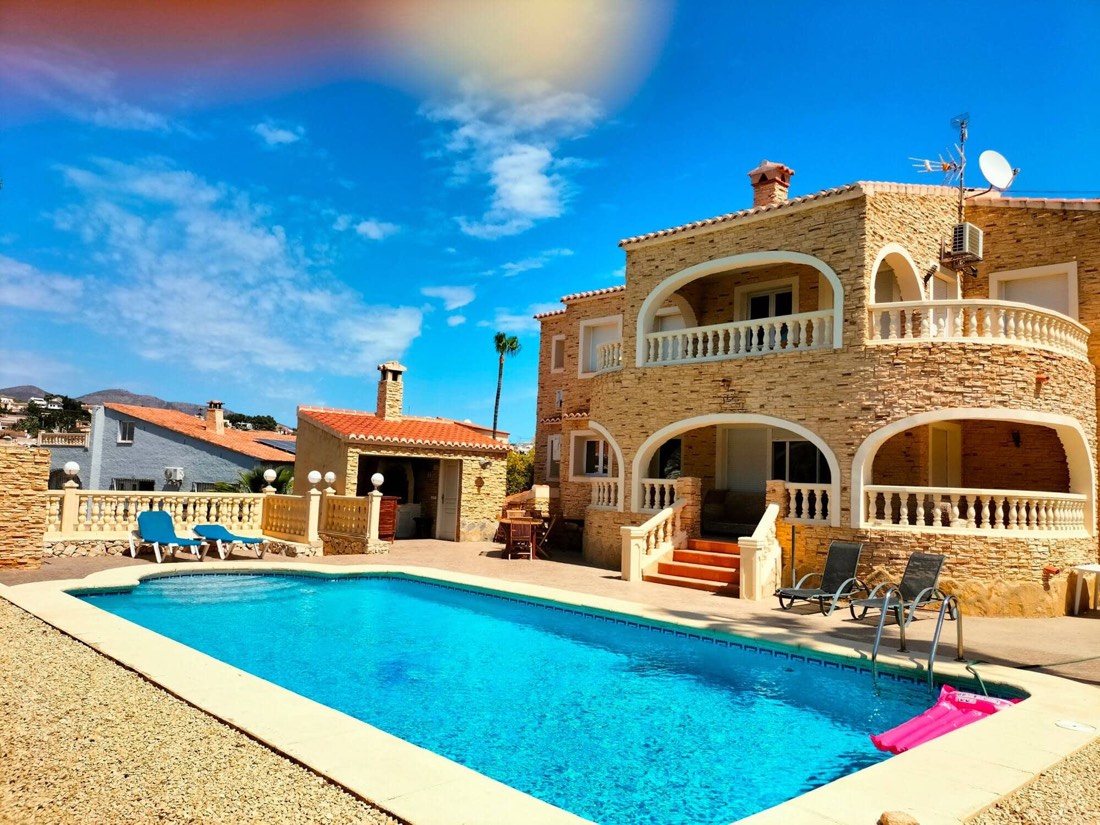 Fachada de piedra de Villa Los Almendros con la piscina en primer término