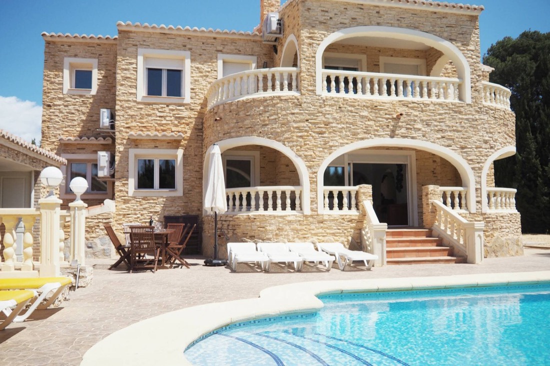 La casa vista desde el otro lado de la piscina, con los arcos y las tumbonas al sol