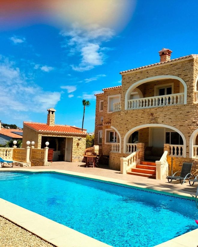 Piscina de Villa Los Almendros delante de la fachada de piedra con arcos