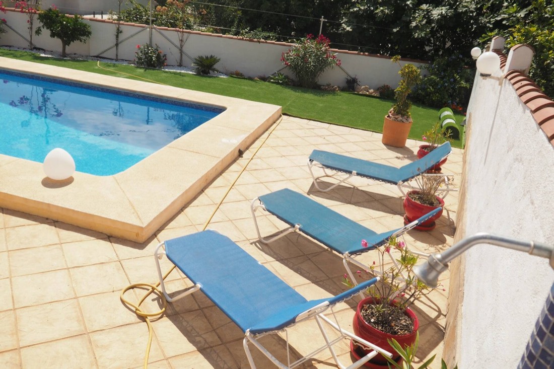 La piscina de Villa Yasmin con las tumbonas y el césped del jardín