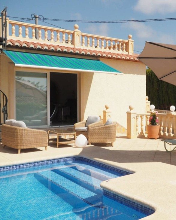 Terraza de Villa Yasmin con los sillones de mimbre bajo el toldo y la piscina delante