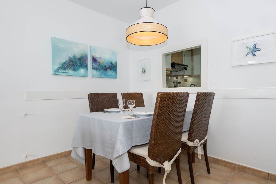 Comedor con la mesa vestida de blanco y cuatro sillas