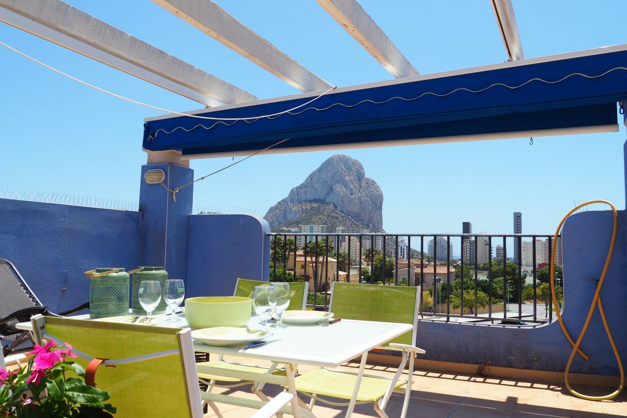 Terraza de apartamento en Calpe con la mesa puesta bajo el toldo y el Peñón de Ifach al fondo