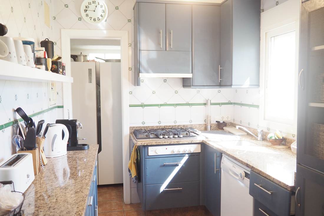 Cocina con los armarios grises, la placa de gas y el lavavajillas